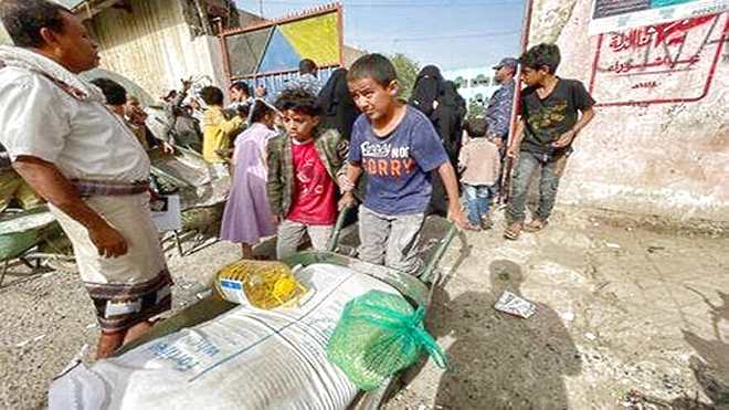 طفلان يمنيان يحصلان لعائلتهما على مساعدات غذائية من منظمة أممية (رويترز)